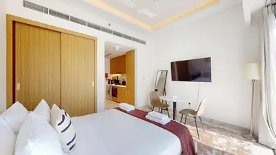 a bedroom with a large white bed and a table at Modern Furnished Studio Azizi Riviera in Dubai