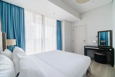 a white bedroom with a large bed and a window at Settler Homes - Premium Matrix Tower with Hot Tub in Dubai