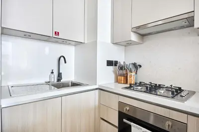 a white kitchen with a sink and a stove at Frank Porter - The Crest Tower, Sobha Hartland in Dubai