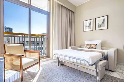 a bedroom with a bed and a chair and a window at Frank Porter - Avenue Residence in Dubai