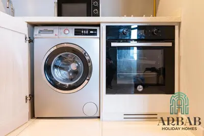 a washing machine and a microwave in a kitchen at Arbab Homes Luxury 1BR - Canal View - Damac Zada Tower in Dubai