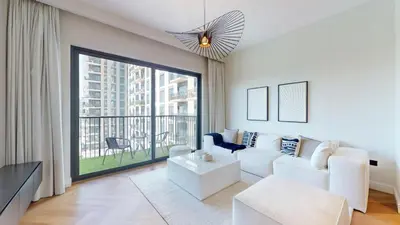 a living room with a white couch and a large window at Vacationer l Upgraded Aesthetic 2 Bed l near Dubai Hills Mall in Dubai