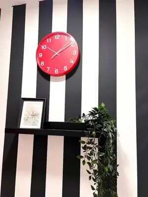 a red clock on a striped wall with a plant at Quiet Comfort Room In Barsha Heights Tecom in Dubai
