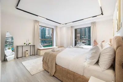 a large white bedroom with a large bed and windows at Chic JBR Apartment Beach Walk Dining Nightlife in Dubai