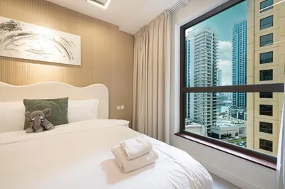 a bedroom with a large window with a teddy bear on a bed at Chic JBR Apartment Beach Walk Dining Nightlife in Dubai