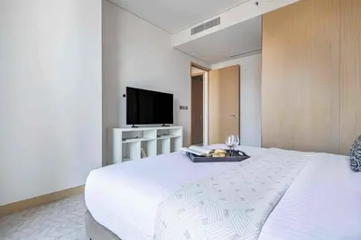 a bedroom with a white bed and a flat screen tv at Frank Porter - Vida Dubai Mall in Dubai