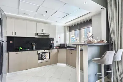 a kitchen with white cabinets and a black counter top at Frank Porter - Opal Tower in Dubai