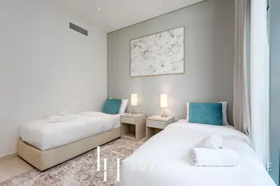 two beds in a room with white walls and blue accents at LUX The Seven Res Palm Suite in Dubai