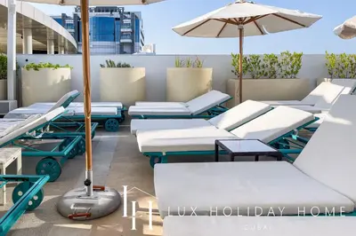 a row of lounge chairs and an umbrella on a rooftop at LUX The Seven Res Palm Suite in Dubai