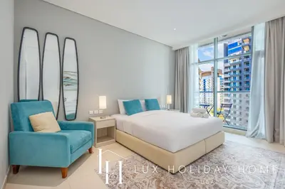 a bedroom with a bed and a blue chair at LUX The Seven Res Palm Suite in Dubai