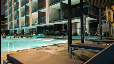 a large building with a swimming pool in front of it at Sleek and Cozy Studio, Private Jacuzzi, Canal View in Dubai