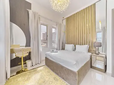 a bedroom with a large bed and a chandelier at Cozy 2BR Canal Residence Sports City in Dubai