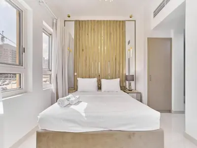 a white bedroom with a large white bed with white sheets at Cozy 2BR Canal Residence Sports City in Dubai