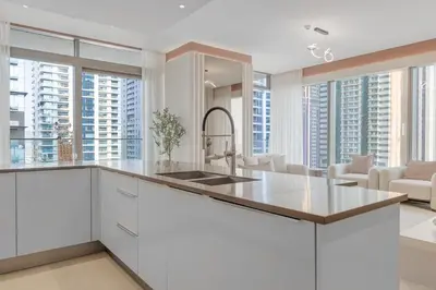 a kitchen with white cabinets and large windows at The Residences Marina Gate 1 - 2 Bedroom Apartment - Allsopp & Allsopp in Dubai