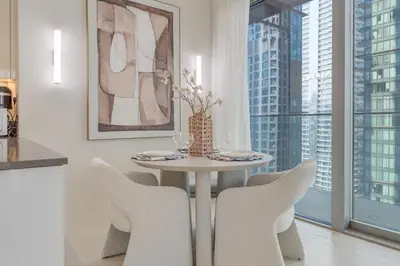 a white dining room with a table and chairs at The Residences Marina Gate 1 - 2 Bedroom Apartment - Allsopp & Allsopp in Dubai