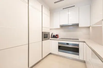 a white kitchen with stainless steel appliances and white cabinets at Canal Front Residence 5, Al Wasl - 2 Bedroom with Maids room - Allsopp & Allsopp 01 in Dubai