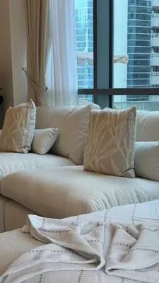 two white pillows on a couch with a window at 1BDR with Huge Balcony Stylish Living in Dubai