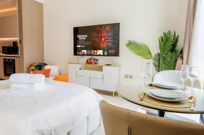 a bedroom with a white bed and a table with chairs at Sleeps 3 Studio JVC I Fully Furnished I Central in Dubai