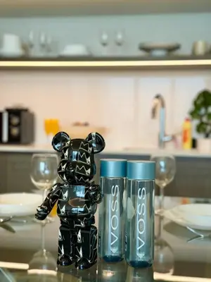 a black toy bear sitting on a table with two cups at Ultra Luxury Emaar Beachfront Flat With Private Beach in Dubai