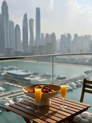 a bowl of fruit on a table with two glasses of orange juice at Ultra Luxury Emaar Beachfront Flat With Private Beach in Dubai