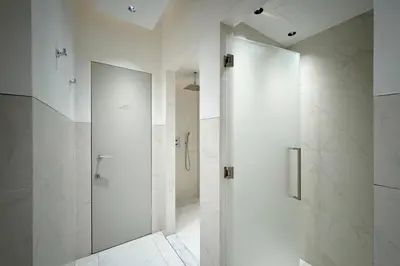 a white bathroom with a shower and a glass door at The Opus Residences 1 Bedroom in Dubai