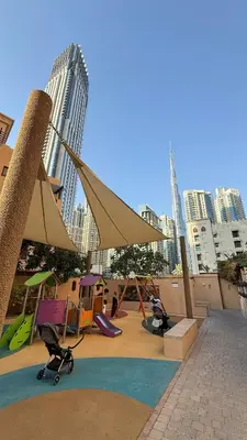 a playground with swings and play equipment in a city at Massive 2,000 sqft 1BR with Private Terrace & BBQ in Dubai