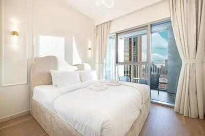 a white bedroom with a large bed and a large window at Modern 2BR, Burj & Fountains View, Dubai Mall 2 Minutes Walk in Dubai