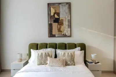a bed with a green headboard and white pillows at Modern Studio JVC I Sleeps 3 I Fully Furnished in Dubai