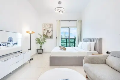 a white room with two beds and a tv at Elegant Minimal Studio with Balcony in Dubai