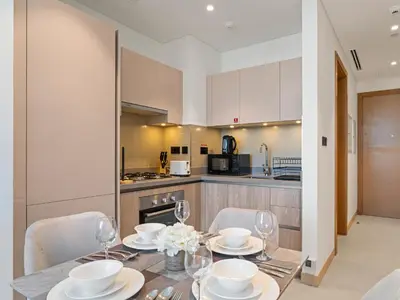 a dining room with a table and chairs and a kitchen at Luxury 1BR Featuring Guest - Study Room-SOBHA Waves in Dubai
