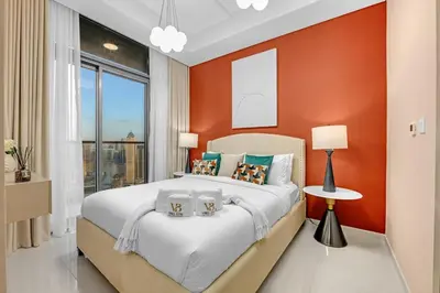 a bedroom with a large bed with an orange wall at Stylish 2BR Canal Views, High Floor in Dubai