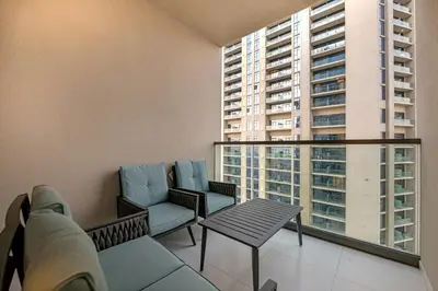 a balcony with a couch and chairs and a table at Stylish 2BR Canal Views, High Floor in Dubai