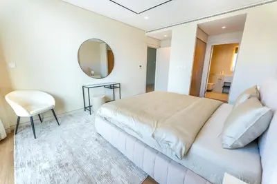 a bedroom with a bed and a mirror and a chair at Exquisite Jumeirah Bay Island Retreat 3 BR plus maids room in Dubai