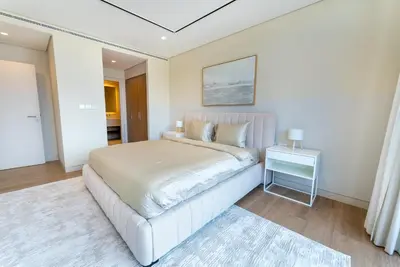 a white bedroom with a large bed and a table at Exquisite Jumeirah Bay Island Retreat 3 BR plus maids room in Dubai