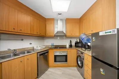 a kitchen with wooden cabinets and a stainless steel refrigerator at Stunning 1BR Apartment with Breathtaking Marina Views in Dubai
