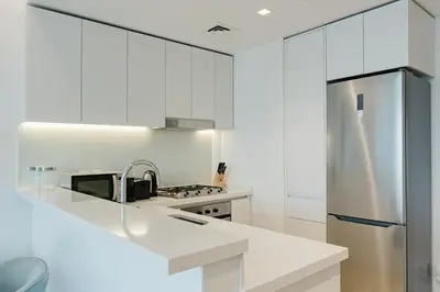a kitchen with white cabinets and a stainless steel refrigerator at RH- Premium Furnished Living in Business Bay near to Burj Khalifa in Dubai