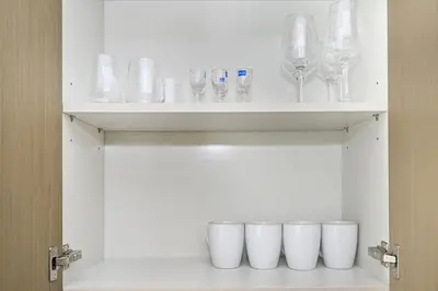 a row of glasses on a shelf in a cabinet at Golden Stays - Tranquil 4BR Villa with Pool & Coastal Charms in Dubai
