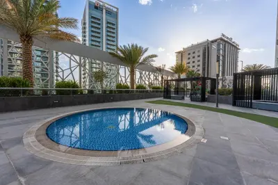 a swimming pool in a courtyard with palm trees and buildings at Stylish Bella Rose Stay Pool & Gym in Dubai