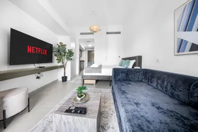 a living room with a blue couch and a tv at Stylish Bella Rose Stay Pool & Gym in Dubai