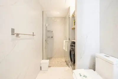 a white bathroom with a toilet and a washing machine at Luxury 1BR Lake View Near Metro & Marina in Dubai