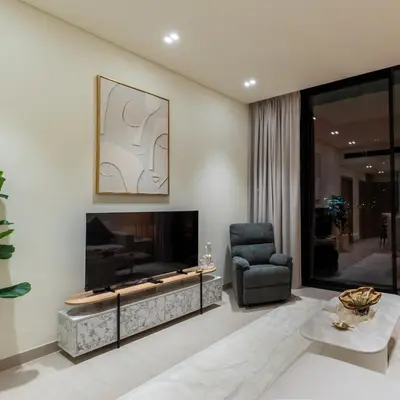 a living room with a large television and a chair at Brand new apartment with luxury furniture in JVC in Dubai