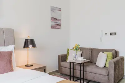 a living room with a couch and a chair at RH-Smart Studio Near Expocity & Al Maktoum Airport in Dubai