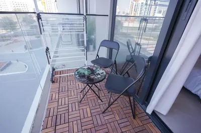 a room with two chairs and a table on a balcony at Stylish modern studio near Miracle Garden with Gym, Pool and Padel court in Dubai