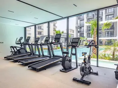 a gym with a row of treadmills in a building at Stylish modern studio near Miracle Garden with Gym, Pool and Padel court in Dubai