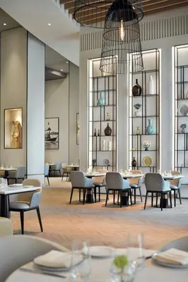 a dining room with tables and chairs and windows at Highest 1BR in JW Marriott Marina with Marina Views in Dubai