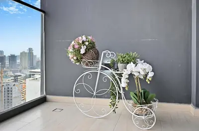 a white plant stand with flowers and potted plants at Golden Stays - Chic 1BR Oasis Serene & Private in Dubai
