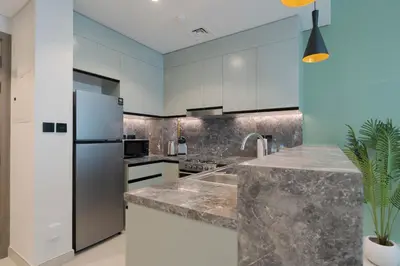 a kitchen with white cabinets and a stainless steel refrigerator at KeyRock Living - Luxury Apartment with Pool & Gym in Dubai