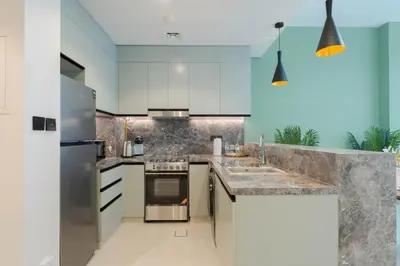 a kitchen with white cabinets and stainless steel appliances at KeyRock Living - Luxury Apartment with Pool & Gym in Dubai