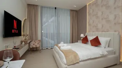 a bedroom with a white bed and a desk and a television at NEW Studio in JVC with Pool View in Dubai