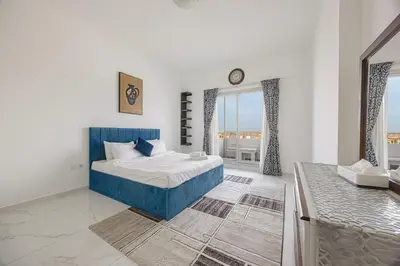 a bedroom with a blue bed and a large window at FiveX Premium 2BR with Extra Room in Dubai